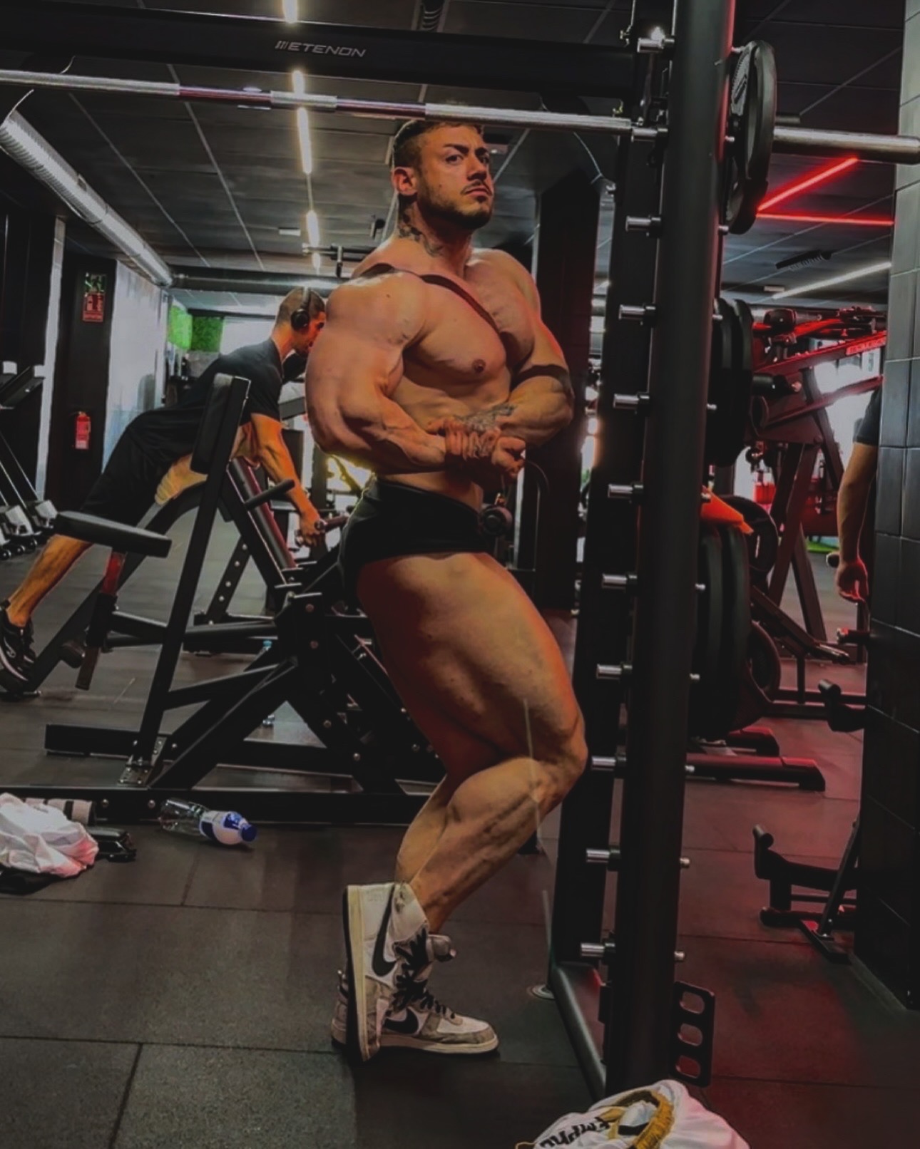 Pose de pecho lateral junto al rack del gimnasio